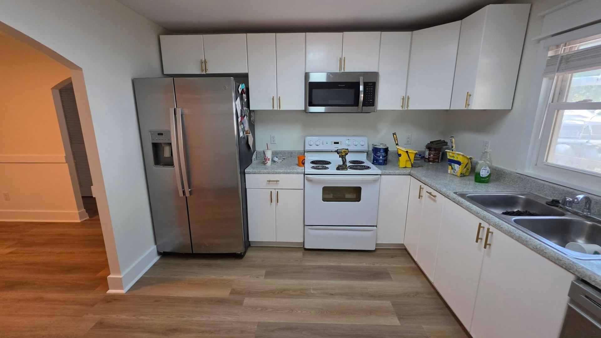 Kitchen after — white cabinets with brass pulls and stainless appliances