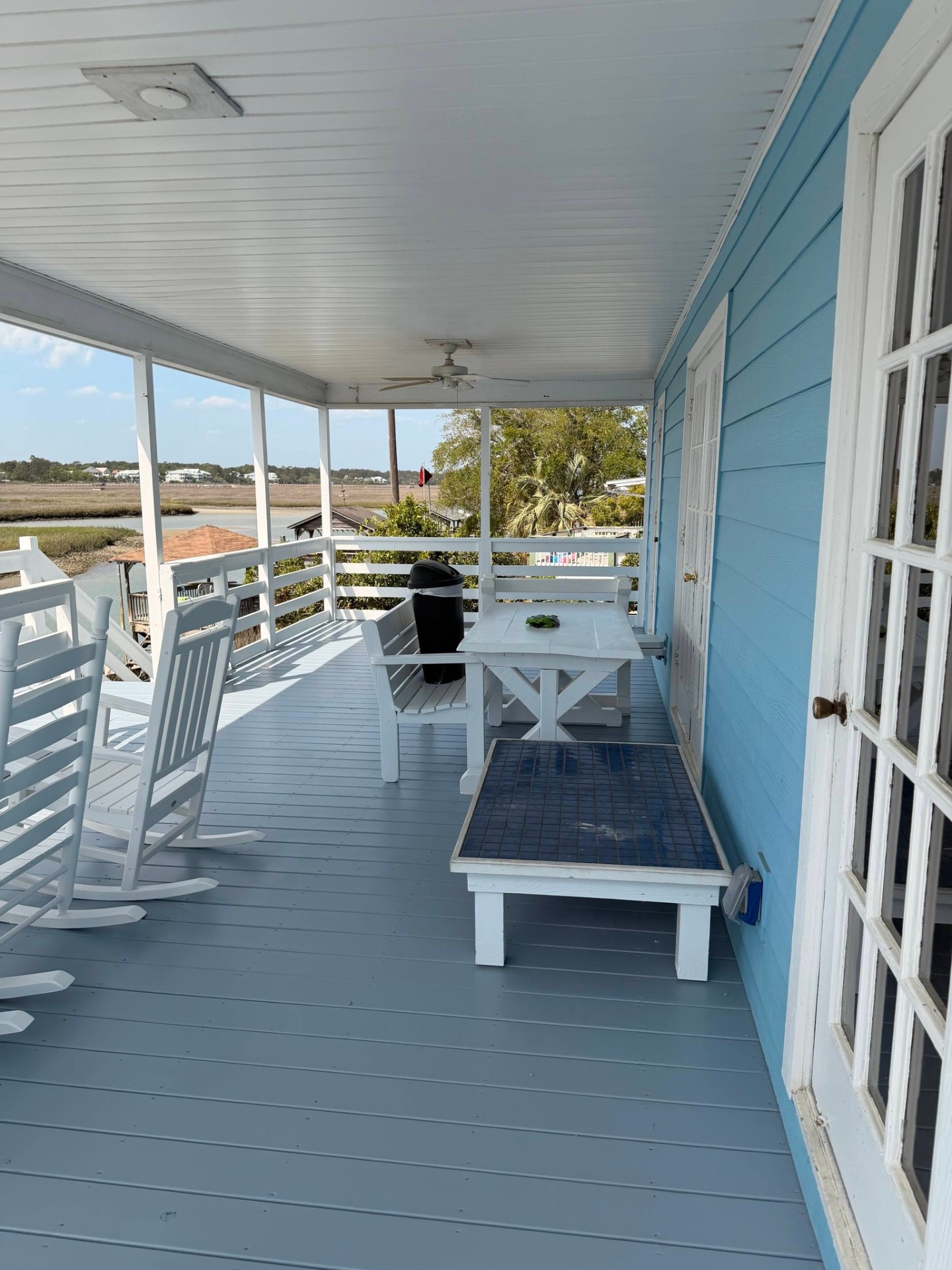 Covered porch with light blue deck boards and white rocking chairs