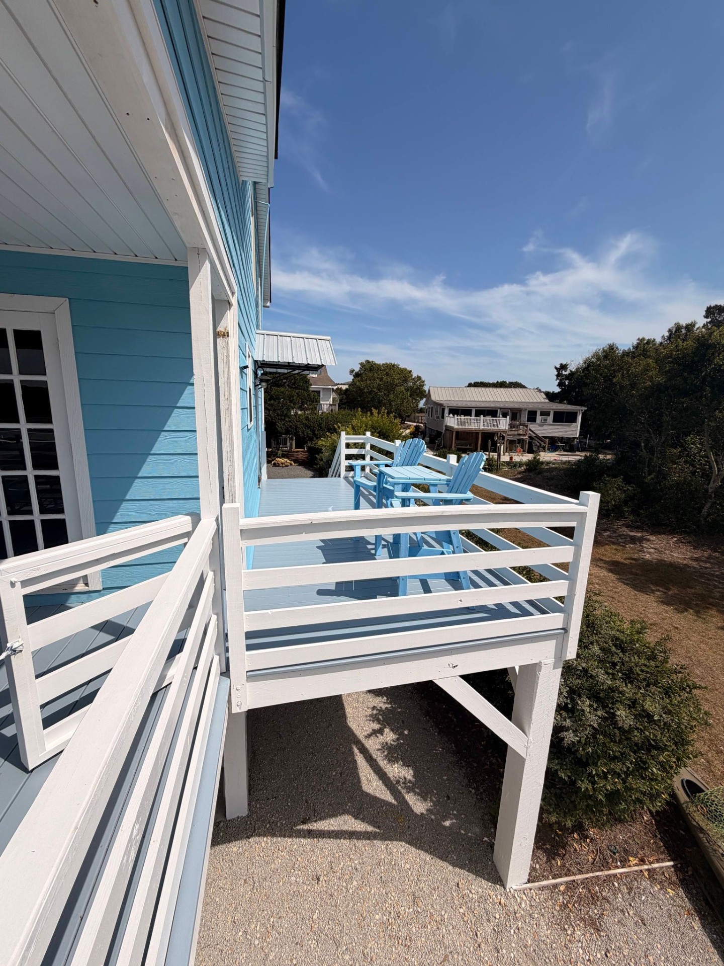 Beachy blue deck with Adirondack chairs and freshly painted railings