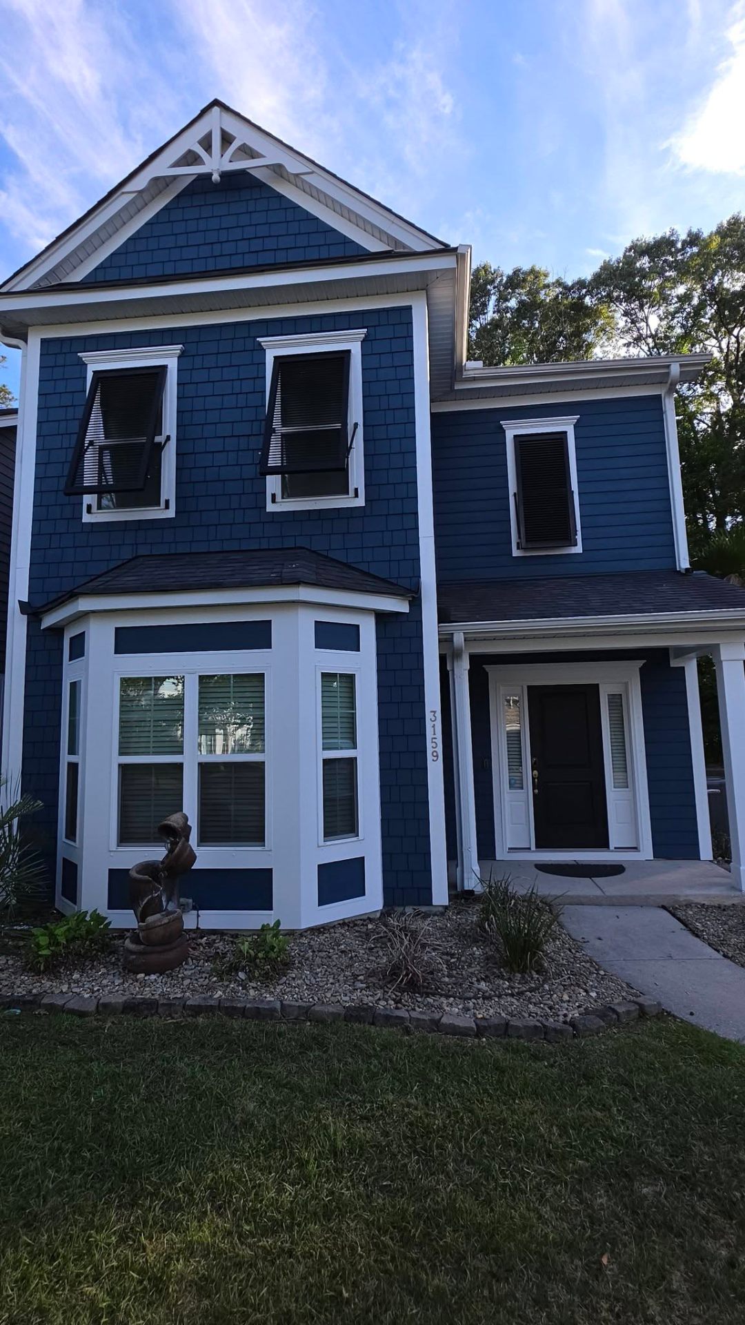 Two-story coastal home with fresh navy siding and bay window trim